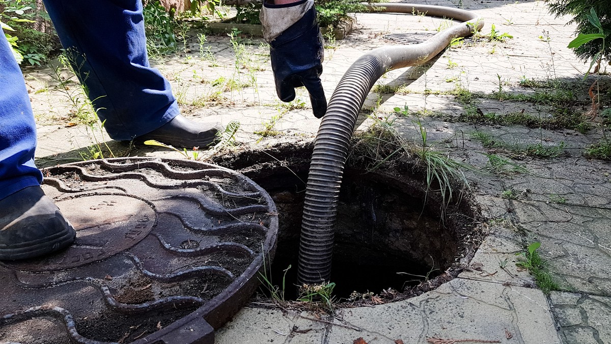 the worker opened the sewer hatch and inserted a hose for cleaning the septic tank. maintenance of communications in a private house